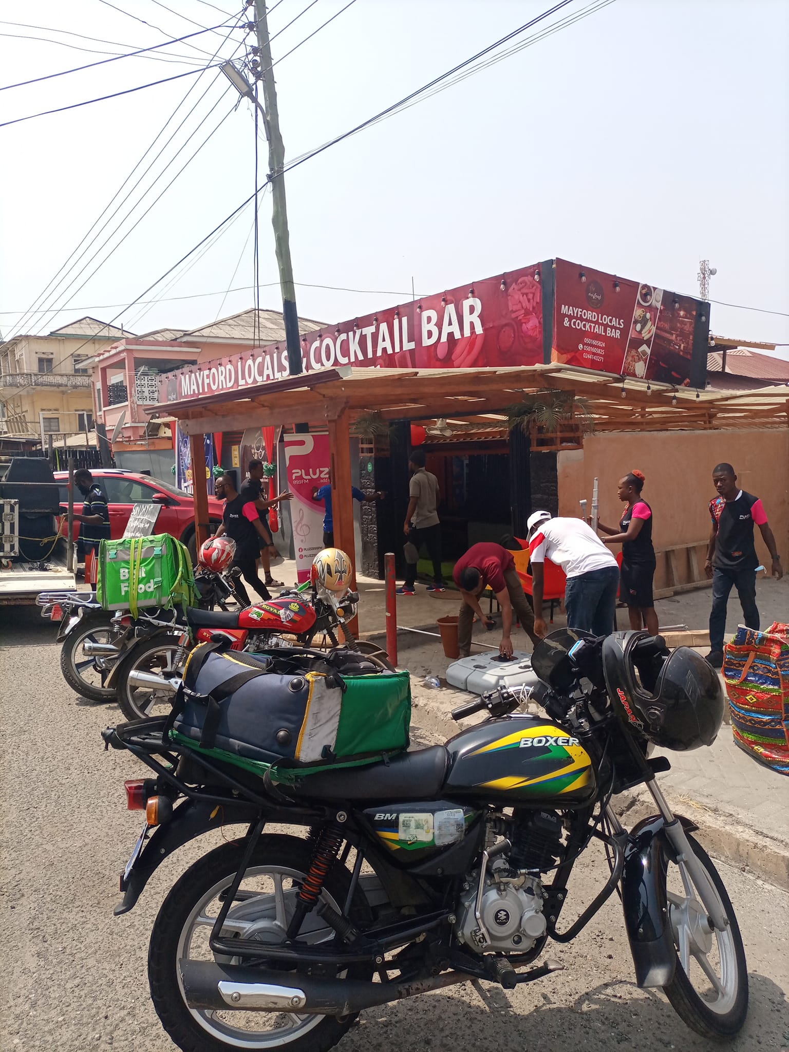 Laughing brown haired woman with food and drink in front of her.
